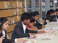 CMR Students studying a Newspaper at the library
